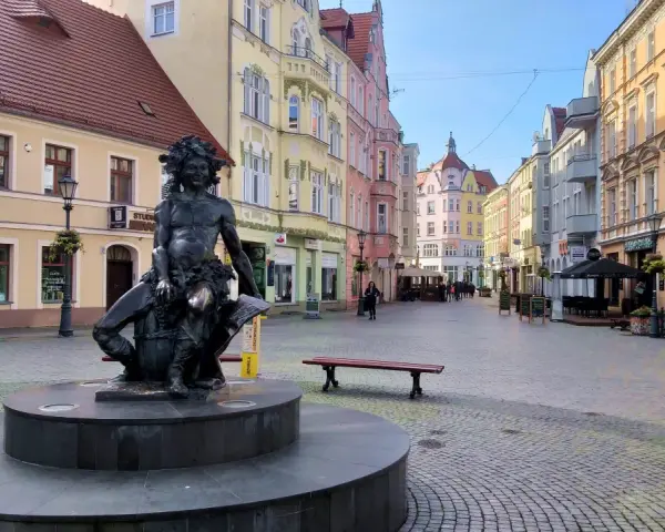 Fontanna z postacią Baccha na brukowanym placu, otoczona kolorowymi kamienicami. Zielona Góra atrakcje turystyczne.