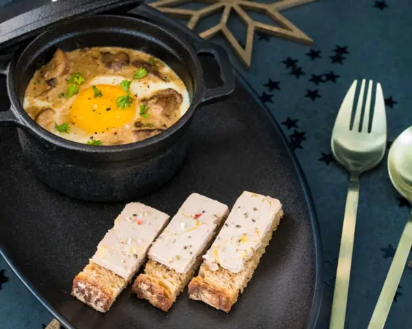 Œuf cocotte aux champignons et foie gras, servi avec des toasts. Un délice pour une recette de fête.