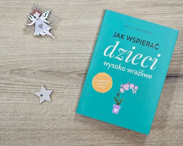Książka "Jak wspierać dzieci wysoko wrażliwe" obok aniołka i gwiazdki.