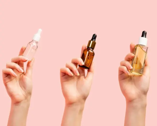Trzy dłonie trzymają buteleczki z serum. Zastanawiasz się, jakie serum do twarzy po 40. wybrać?