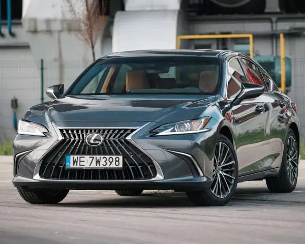 Elegancki, ciemnoszary Lexus 300h z brązowym wnętrzem stoi na parkingu.