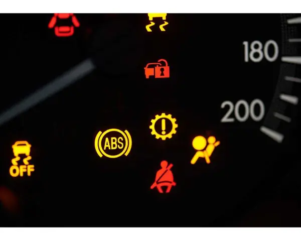 Cruscotto auto con spia ABS accesa fissa, insieme ad altre spie di avaria.
