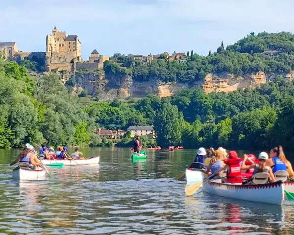 Des gens en canoë sur une rivière, avec un château en arrière-plan.