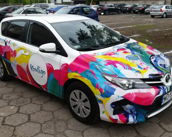 Kolorowe oklejone samochody z logo "Koutigo" na parkingu.