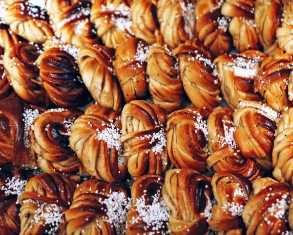 En stor bricka med gyllenbruna kanelbullar, en svensk specialitet, toppade med pärlsocker.
