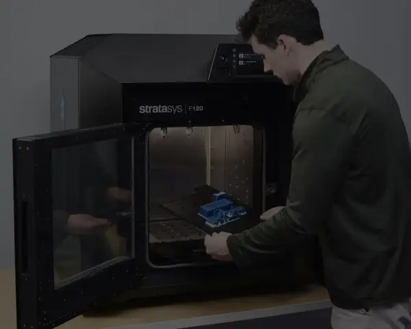 Mężczyzna wkłada wydrukowany model do drukarki 3D Stratasys F120. Tak wygląda drukarka 3d w akcji.