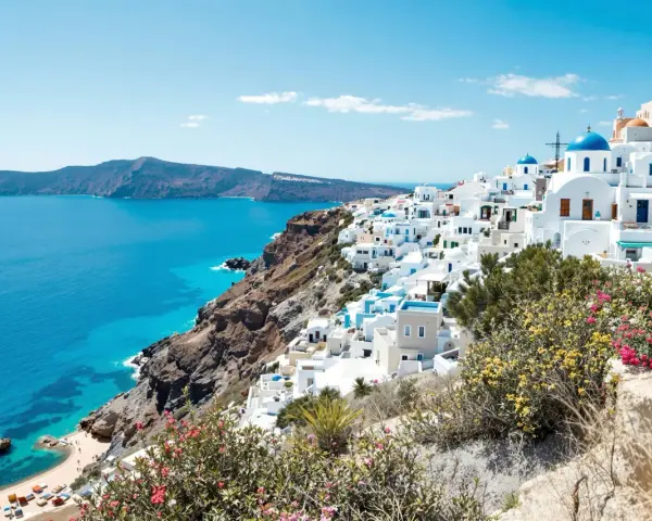 Vue panoramique de Santorin, Grèce, avec des maisons blanches et des dômes bleus surplombant la mer Égée.