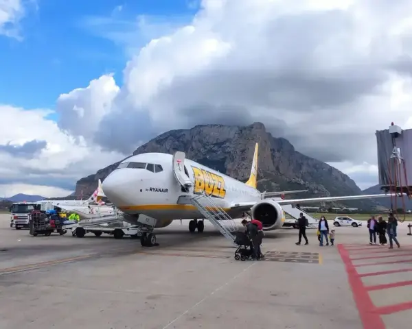 Samolot Buzz by Ryanair na lotnisku na Sycylii, z górami w tle.