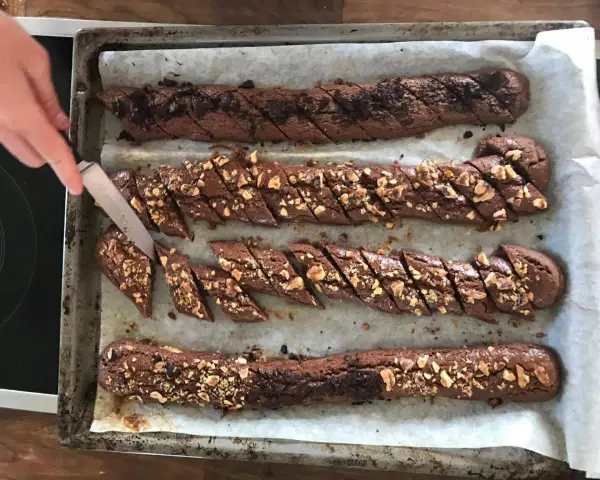 Chokladsnittar recept: Nybakade chokladkakor med nötter och chokladbitar skärs upp på en plåt.