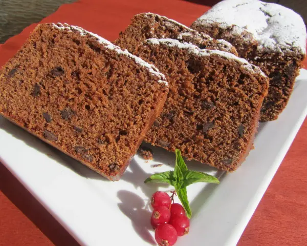 Rebanadas de bizcocho de colacao con trocitos de chocolate, espolvoreado con azúcar glas y decorado con grosellas y menta.