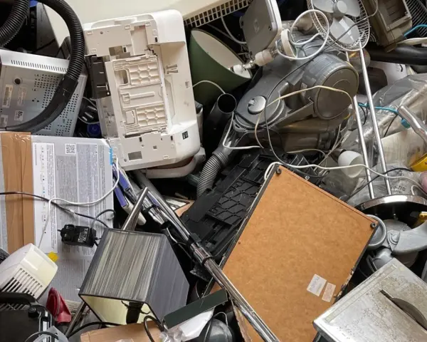 Stary sprzęt AGD, w tym odkurzacz i drukarka, tworzą stos. Zastanawiasz się, gdzie wyrzucić żelazko? To miejsce to idealny przykład elektrośmieci.