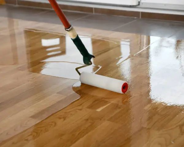 Application d'une couche de vitrificateur sur un parquet en bois. Le temps de séchage entre 2 couches est crucial pour un résultat parfait.