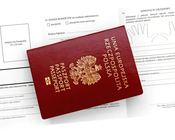 Czerwony paszport leży na formularzu. Czy wniosek o paszport można złożyć online? Formularz zawiera rubryki na dane, zgodę rodziców i odciski palców.