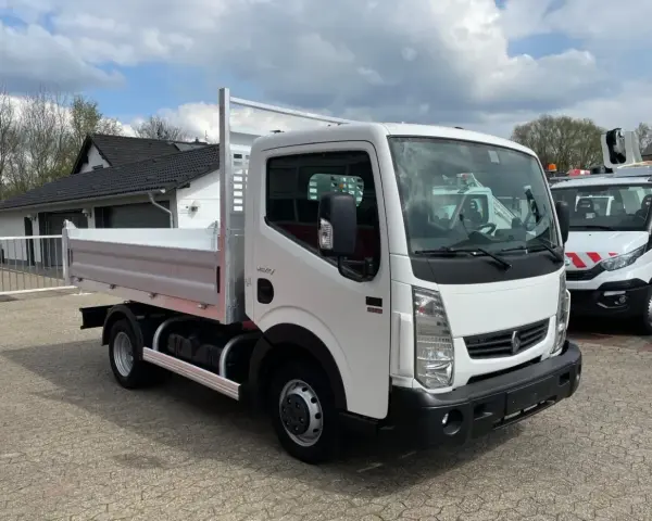 Biały Renault Maxity z otwartą skrzynią ładunkową stoi na placu. W tle budynek i inne pojazdy.