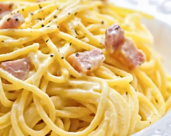 Un plato de pasta cremosa con trozos de panceta y pimienta negra molida, una auténtica carbonara original.