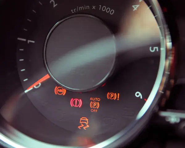 Dashboard lights illuminate, including ABS, brake warning, and a car skidding, indicating a potential issue with the slip indicator light.