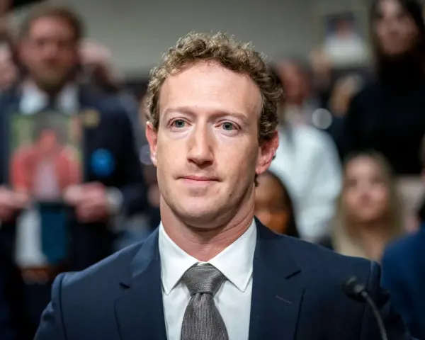 Mark Zuckerberg im Anzug, im Hintergrund unscharfe Menschen und ein Foto.