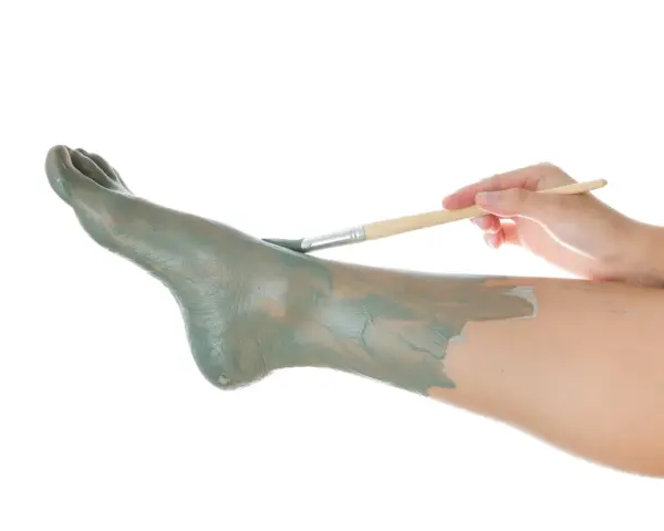 Application d'un masque d'argile sur un pied, comme un soin pour un clou au pied.