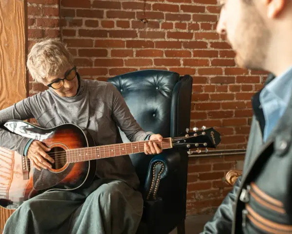 Kobieta gra na gitarze w szkole muzycznej dla dorosłych. Lekcja z nauczycielem.