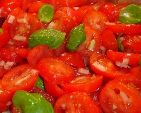 Frischer Tomatensalat mit Zwiebeln und Basilikum, bereit für ein leichtes Tomatensalat Dressing.