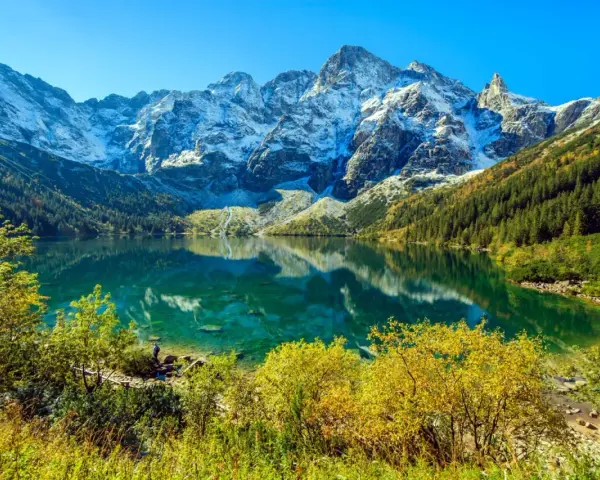 Piękny widok na Morskie Oko, gdzie szczyty górskie odbijają się w krystalicznie czystej wodzie. Ile się idzie na Morskie Oko? To zależy od tempa, ale widok wynagradza każdy krok.