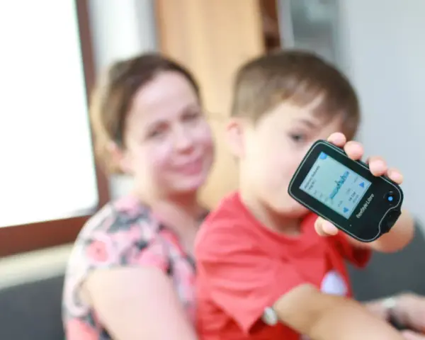Chłopiec z mamą monitoruje poziom glukozy, co może być związane z objawami cukrzycy u dzieci.