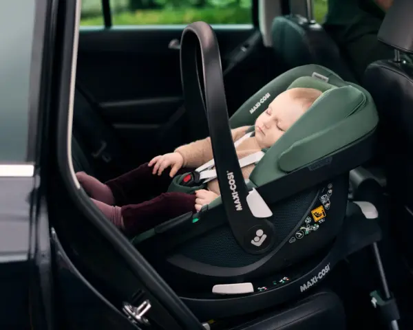 Schlafendes Baby in einer grünen Babyschale mit Isofix-Autobefestigung. Sicher und bequem auf Reisen.