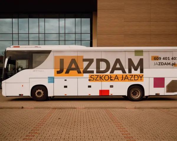 Biały autobus szkolny z napisem "JAZDAM SZKOŁA JAZDY" i numerem telefonu. Idealny do nauki jazdy kategorii D.