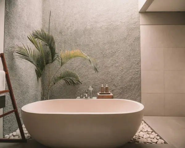 Ett modernt badrum med fristående badkar, en grå texturerad vägg och en palm. Perfekt för att renovera badrum och skapa en spa-känsla.
