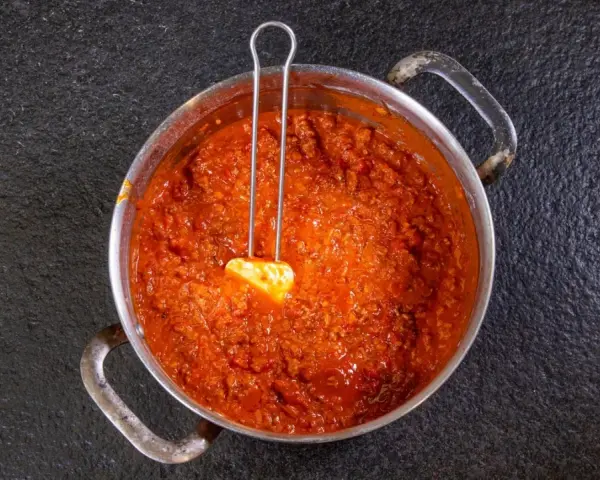 Herzhaftes Ragu in einem Topf, bereit für ein köstliches Ragu Rezept. Ein Löffel mit Butter liegt darin.