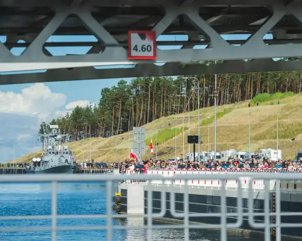 Uroczyste otwarcie przekopu Mierzei Wiślanej. Na wodzie okręt, na brzegu tłumy widzów.