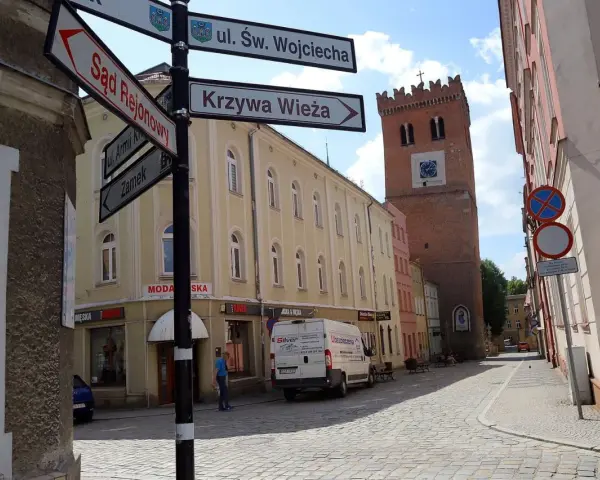 Ulica z wieżą i drogowskazami do Sądu Rejonowego, Krzywej Wieży i Zamku. Odkryj mało znane miejsca na Dolnym Śląsku.