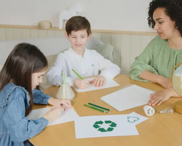 Dzieci i nauczycielka tworzą scenariusz zajęć "z ekologią na ty". Na stole symbol recyklingu, żarówki i globus.
