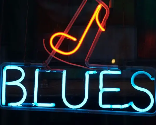 Néon bleu lumineux "BLUES" avec une note de musique rouge orangé au-dessus. L'ambiance parfaite pour une soirée blues.