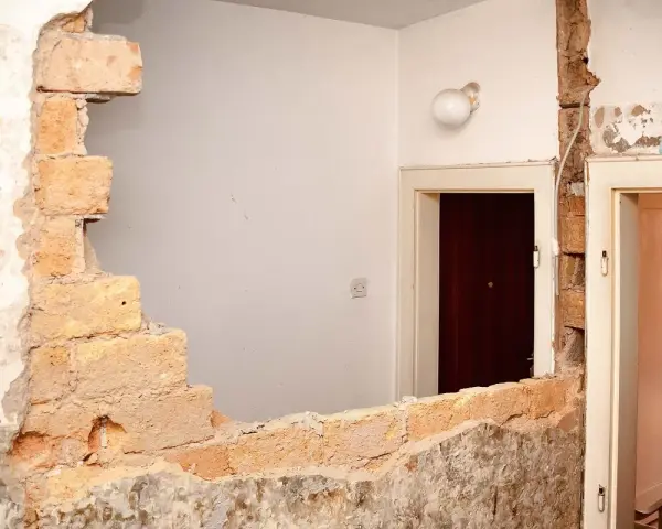 Rozbiórka budynku, odsłonięta wspólna ściana z cegieł między drzwiami.