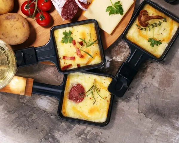 Pyszne, roztopione sery z dodatkami w patelenkach do raclette. Idealne na wspólne wieczory, gdy zastanawiasz się, co na raclette.
