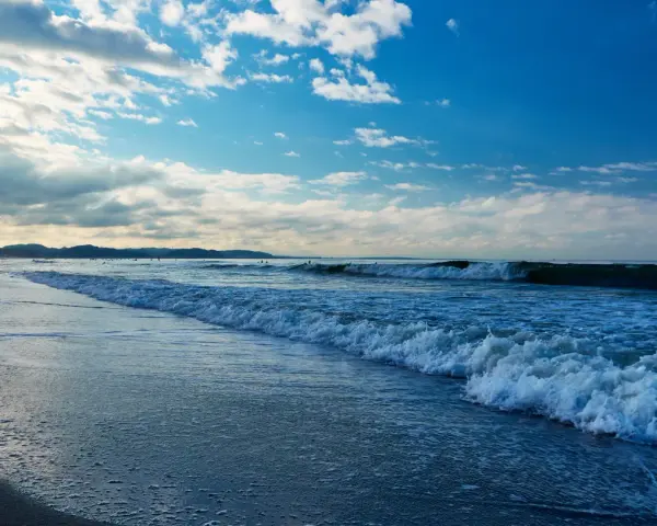 Plaża nad Bałtykiem z falami i błękitnym niebem z chmurami.