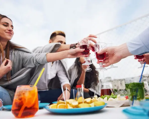 Grupa przyjaciół wznosi toast czerwonymi drinkami. Czy to już czas na digestif co to?