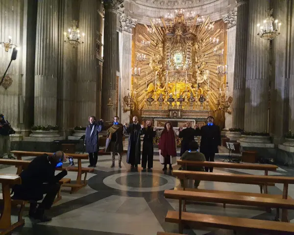 A group of people in a church, some holding hands, with a large golden altar in the background.