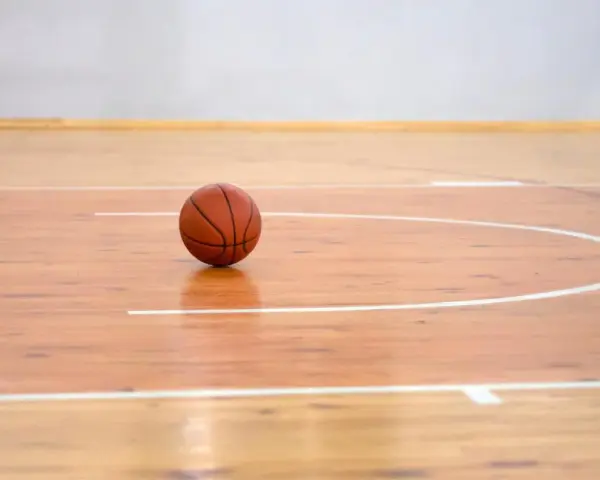 Balón de baloncesto sobre los pavimentos deportivos de madera pulida, listo para el juego.