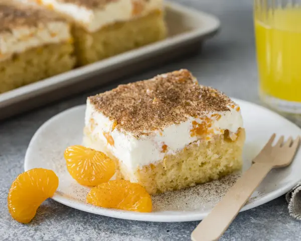 Ein Stück saftiger Fantakuchen mit cremiger Füllung und Mandarinenstücken, bestreut mit Zimt. Perfekt für das Fantakuchen Rezept!