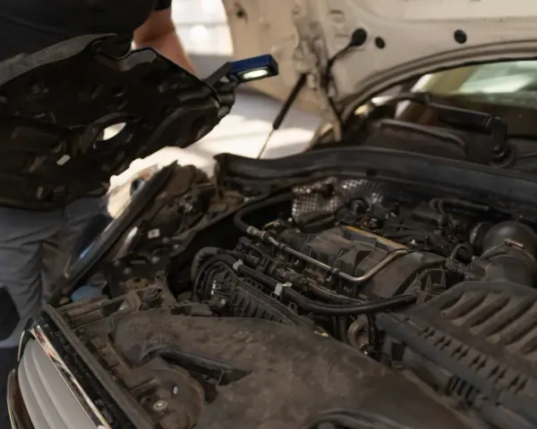 Mechanik sprawdza silnik, szukając objawów przegrzania. Widać elementy silnika i narzędzia.