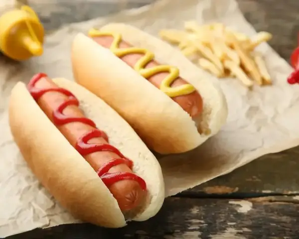 Dwa hot dogi, jeden z keczupem, drugi z musztardą, obok frytek. Zastanawiasz się, ile kalorii ma hot dog?