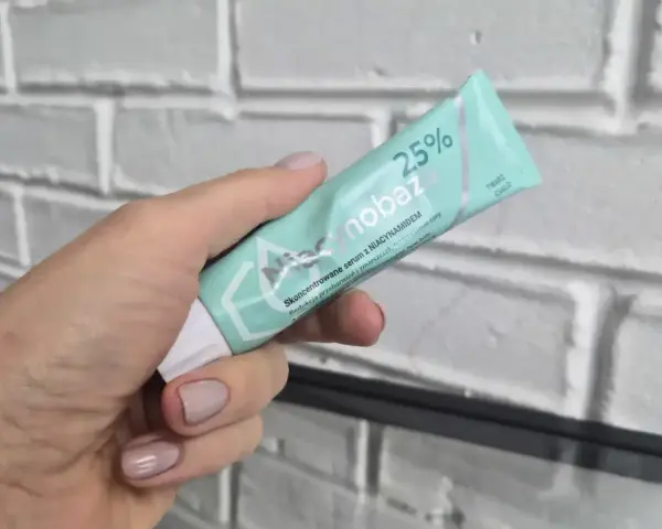 Dłoń trzyma tubkę serum niacynobaza 25%. Wiele pozytywnych opinii o tym produkcie.