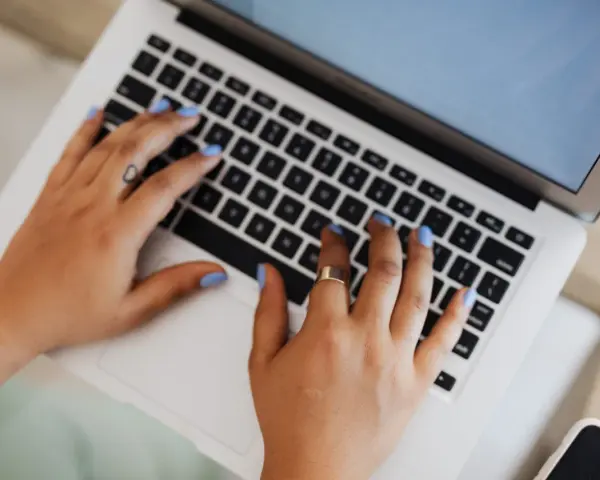Mani che digitano su un laptop, forse per un corso di **università Pegaso**.