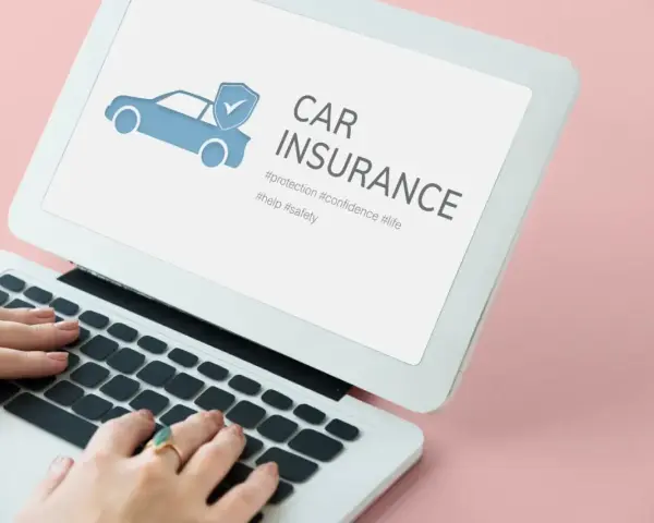 Kobieta wpisuje w laptopie frazę "ile kosztuje ubezpieczenie samochodu pierwszy raz". Na ekranie widnieje grafika samochodu z tarczą i hasło "CAR INSURANCE".