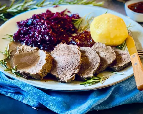 Saftiger Rinderbraten, serviert mit Rotkohl und Klößen – ein köstliches rinderbraten rezept für ein Festmahl.