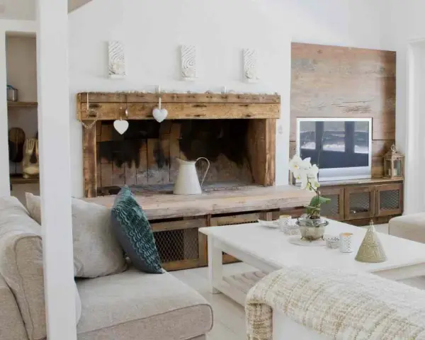 Un camino rustico con decorazioni a cuore e una brocca bianca, un'idea per come decorare un camino in stile country.