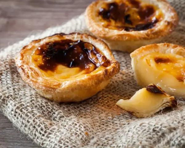 Tre krämiga portugisiska bakelser med karamelliserad yta, en klassiker inom portugisisk mat.