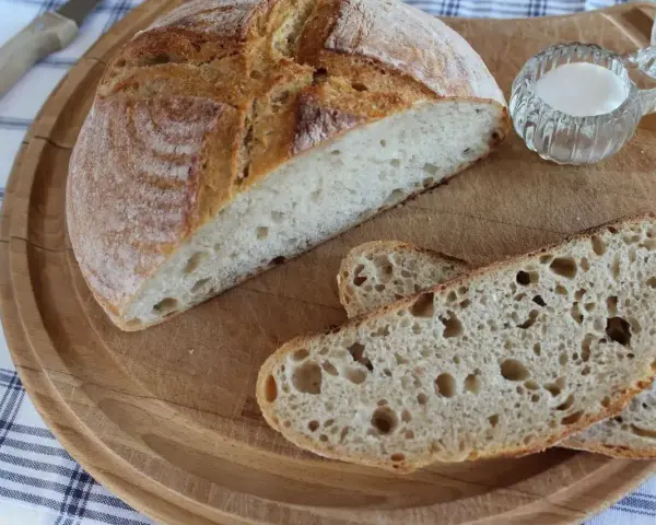 Chleb żytni na zakwasie, pokrojony w kromki, z solniczką na drewnianej desce.
